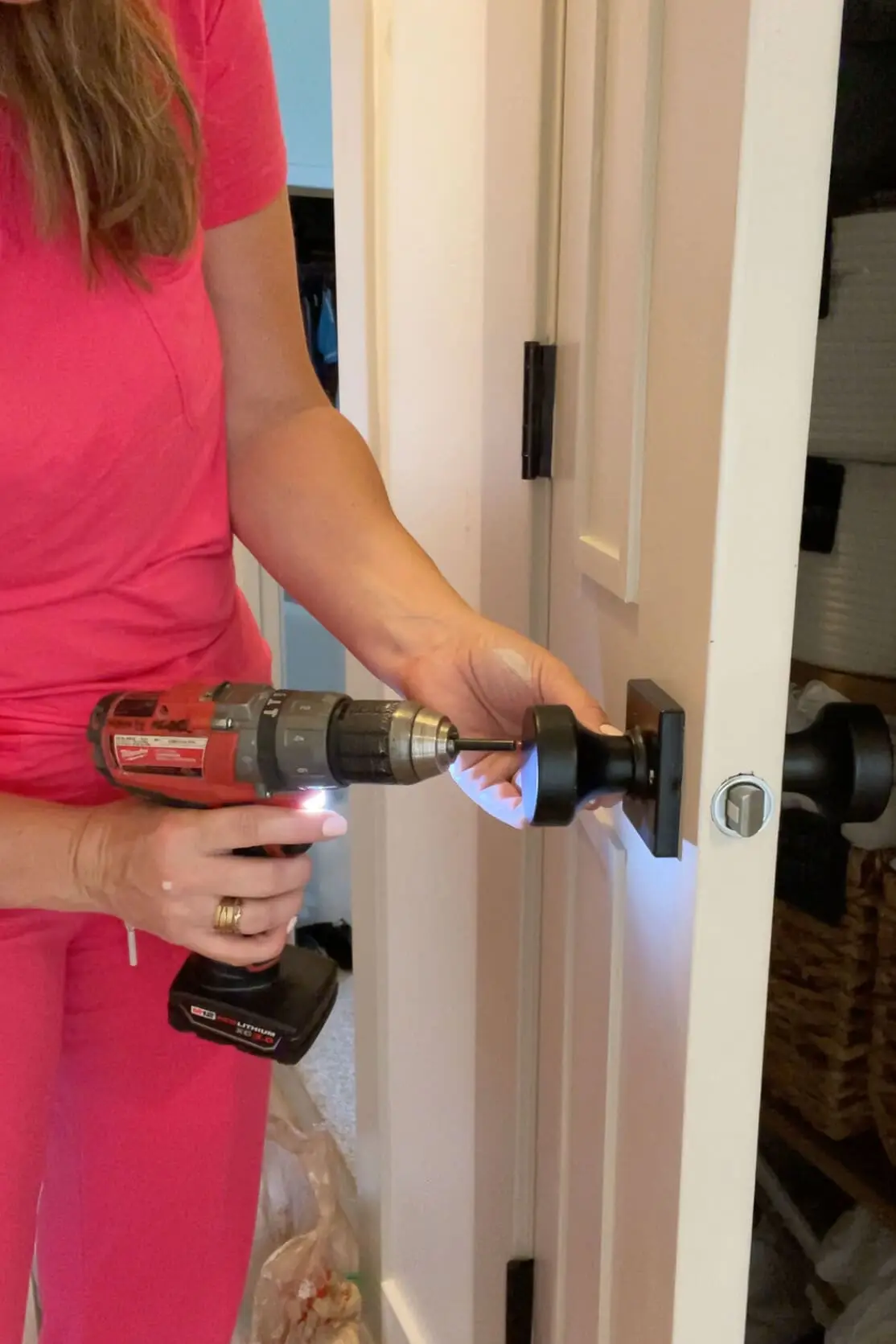 DIY home improvement project—installing a new black door knob using a power drill.